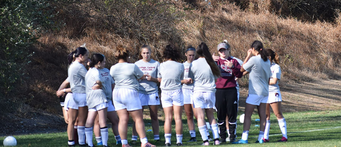 A women's soccer team meets on the field.