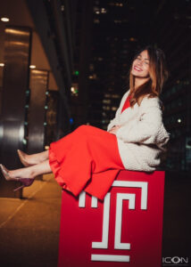 A young woman sits on top of a large red block featuring the Temple University "T".