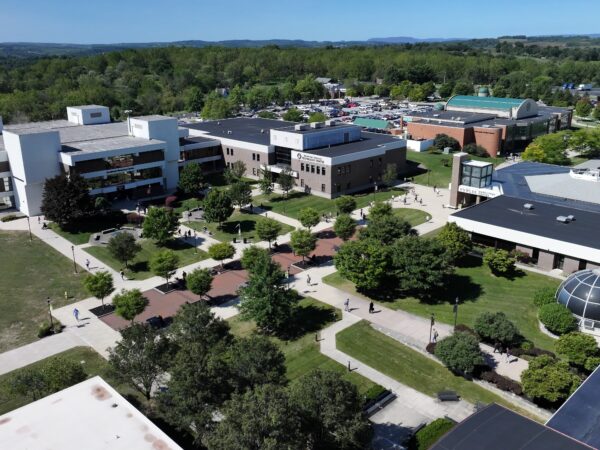 An aerial drone photograph of the Lehigh Carbon Community College (LCCC) main campus, showcasing several academic buildings, winding pedestrian walkways, and landscaped green spaces under a clear blue sky.