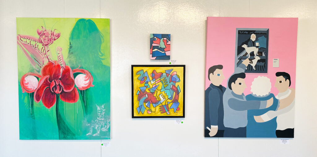 Three art pieces hang on display in the Glass Box Gallery.