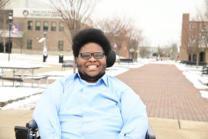Isaiah Natale smiles and poses for a photo on the outdoor mall area at Main Campus.