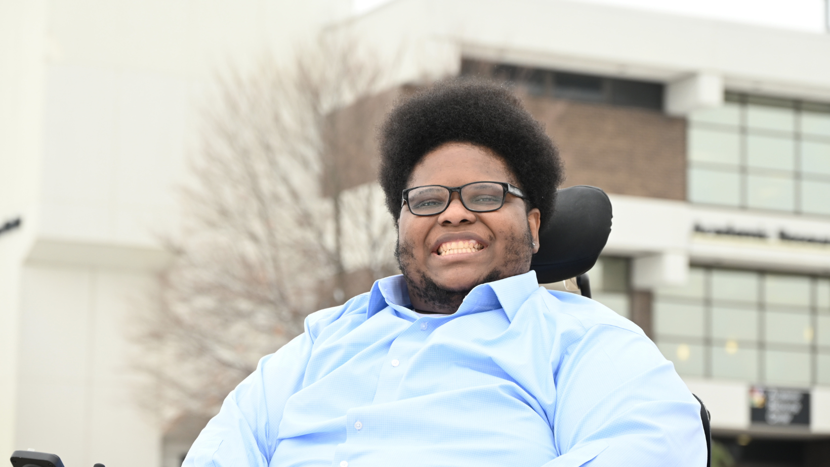 Isaiah Natale smiles and poses in front of the Academic Resource Center at our Main Campus.