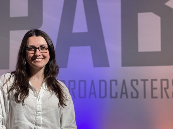 Image shows Makenzie Christman holding her PAB Award in front of a wall that says, "PAB."