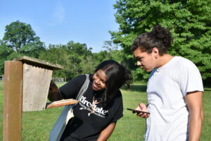 Image shows two students examining a bird box.