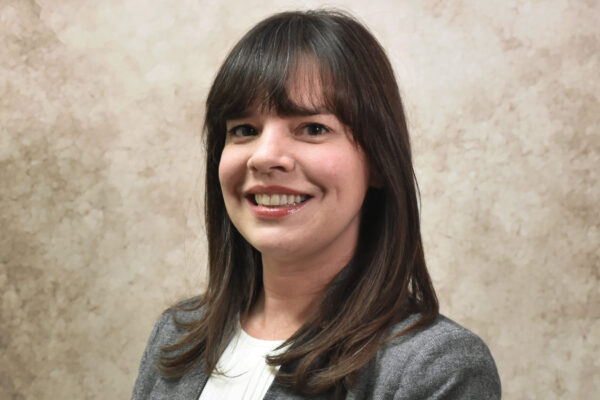 Professional photo of a woman with long brown hair wearing a blazer and white blouse.
