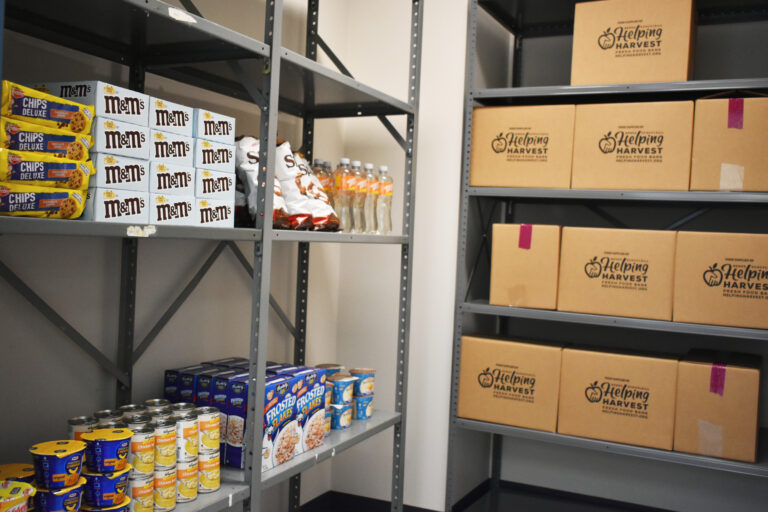 Image shows various packaged goods and Helping Harvest boxes lining the shelves of the Tamaqua Center food pantry.