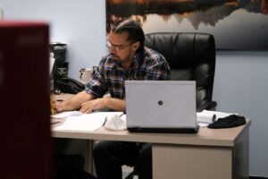 Jose Rivera sits at a desk and looks through paperwork.