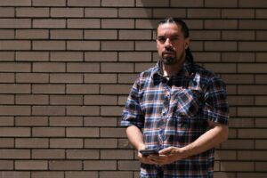 Jose Rivera stands in front of a tan brick wall.