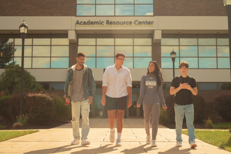 Image shows four students walking in front of the Academic Resource Center.