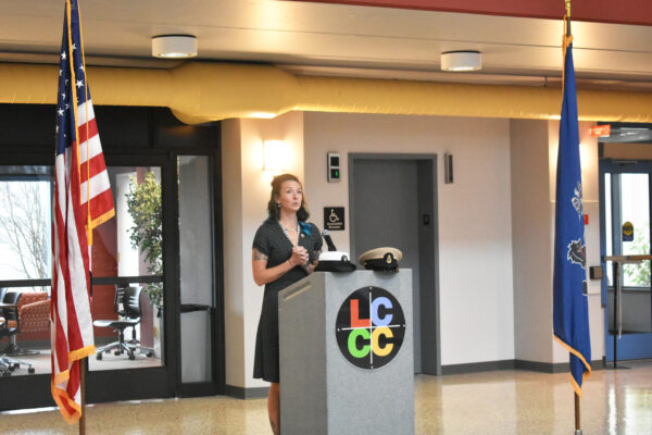 Image shows a veteran student speaking at a podium next to the American and Pennsylvanian flags. The LCCC logo is on the podium.